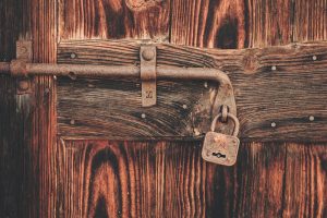 Rusty padlock and sliding bolt on a weathered wooden door