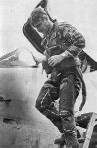 Black-and-white photo of James Stockdale in flight gear climbing from a jet cockpit