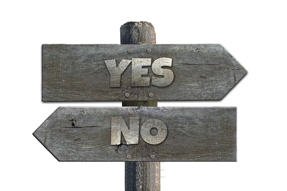 Weathered wooden signpost with arrows labeled YES and NO pointing in opposite directions