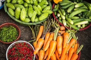Market baskets of fresh vegetables: carrots, cucumbers, chilies, and bitter melons